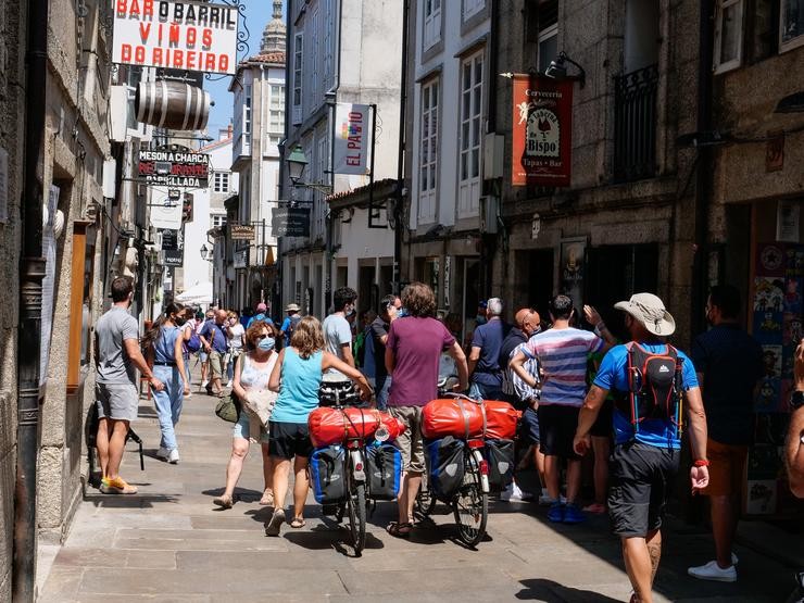 Varios peregrinos camiñan coa súa bicicleta pola Rua do Franco de Santiago. César Arxina - Europa Press / Europa Press