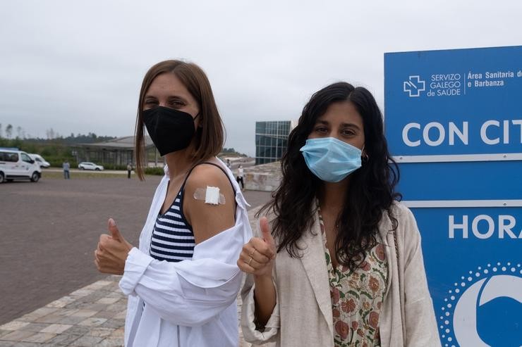 Dous  mozos saúdan tras ser vacinadas contra o Covid-19 no complexo de Cidade da Cultura. César Arxina - Europa Press 