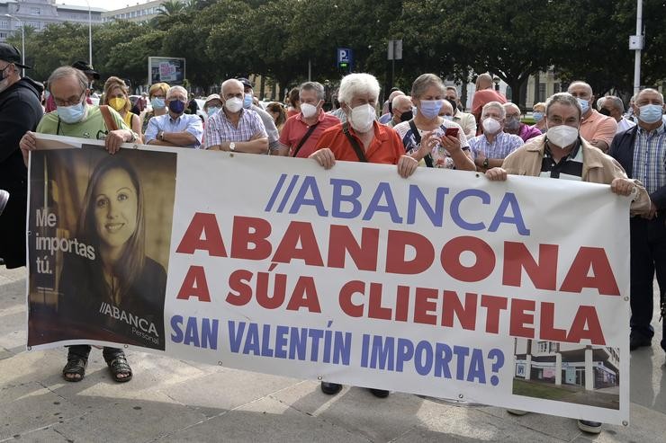 Un grupo de persoas sostén unha pancarta durante a manifestación contra o peche de oficinas da entidade Abanca ante a súa sede na Coruña 
