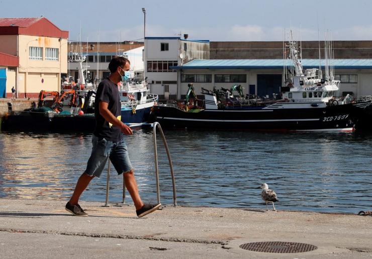 Home camiñando no porto de Burela/AXM