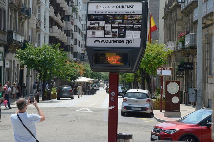 Un home fai unha fotografía a un termómetro na rúa que marca 45 graos, a 12 de xullo de 2022, en Ourense. / Rosa Veiga