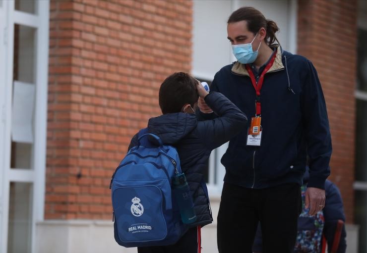 Un traballador toma a temperatura a un neno á súa chegada ao primeiro día de clase presencial tras o Nadal. Isabel Infantes - Europa Press / Europa Press