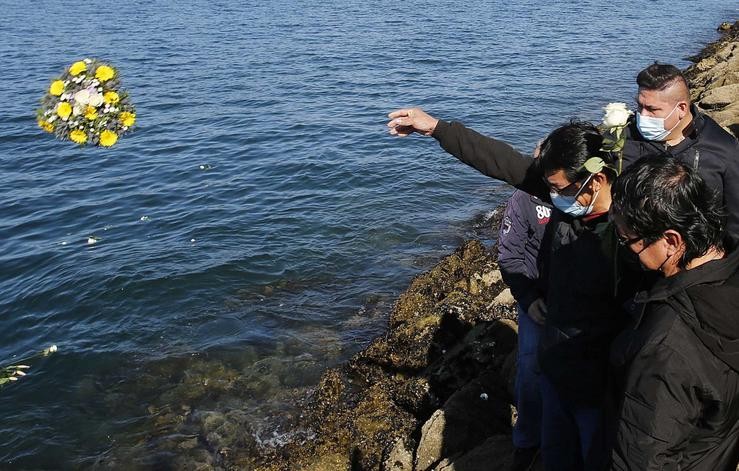 Un home lanza flores ao mar en recordo aos tripulantes do pesqueiro galego afundido en Terranova. Marta Vázquez Rodríguez - Europa Press