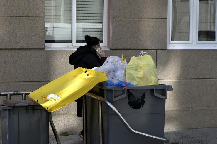 Unha muller pasa por un colector de lixo que soborda no barrio de Monte Alto da Coruña pola falta do servizo de recollida de lixo tras a terceira madrugada de incidentes polo conflito do lixo, a 25 de febreiro de 2022, na Coruña 