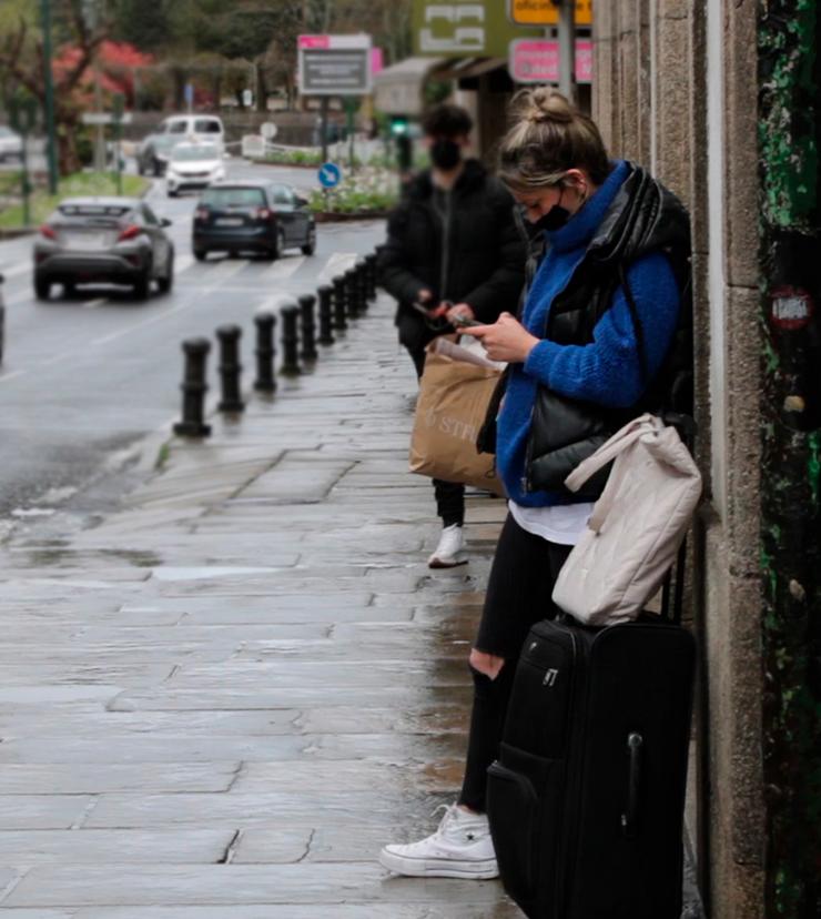 rapaza esperando o autobús cunha maleta en Santiago de Compostela/Paula Daza