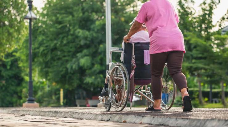 Unha muller coida dunha persoa en cadeira de rodas 