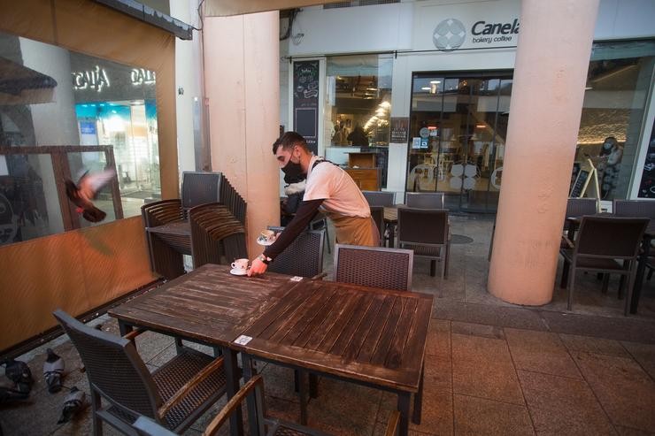 Un camareiro recolle a mesa dunha terraza 