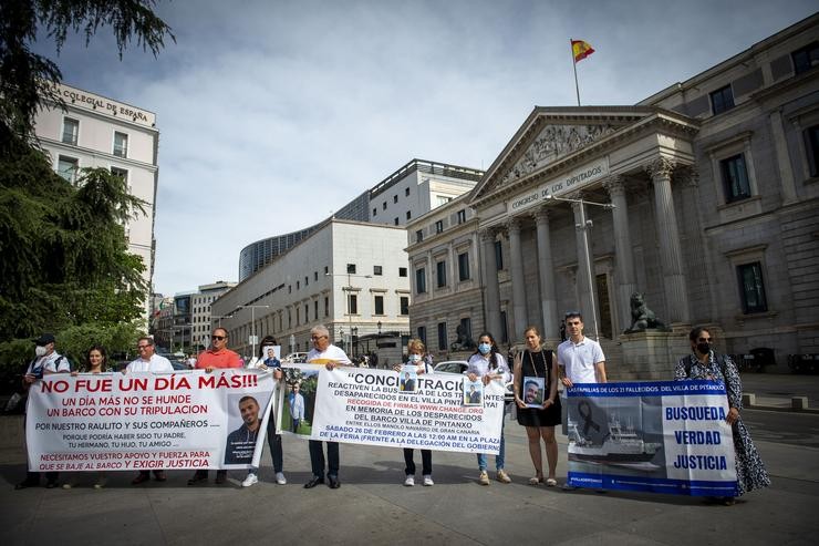 Familiares de mariñeiros falecidos no Villa de Pitanxo sosteñen pancartas e fotografías nunha concentración, ás portas do Congreso dos Deputados 