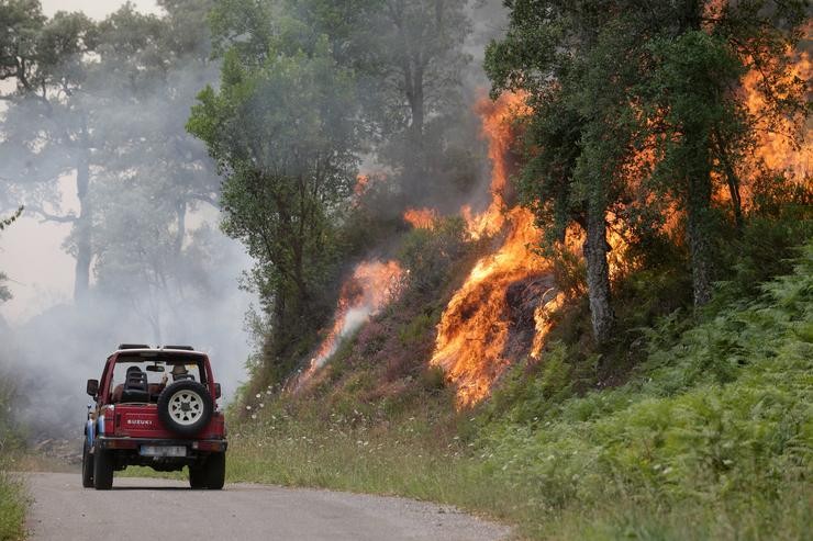 Un coche pasa preto das chamas nun incendio, a 15 de xullo de 2022, en Samos, Lugo 