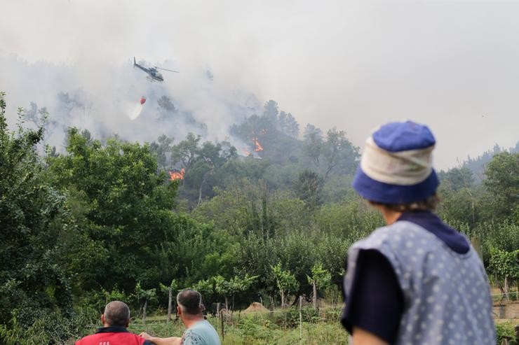 Varias persoas observan como un helicóptero trata de extinguir un lume nas inmediacións dun incendio en Quiroga / Carlos Castro - Europa Press / Europa Press