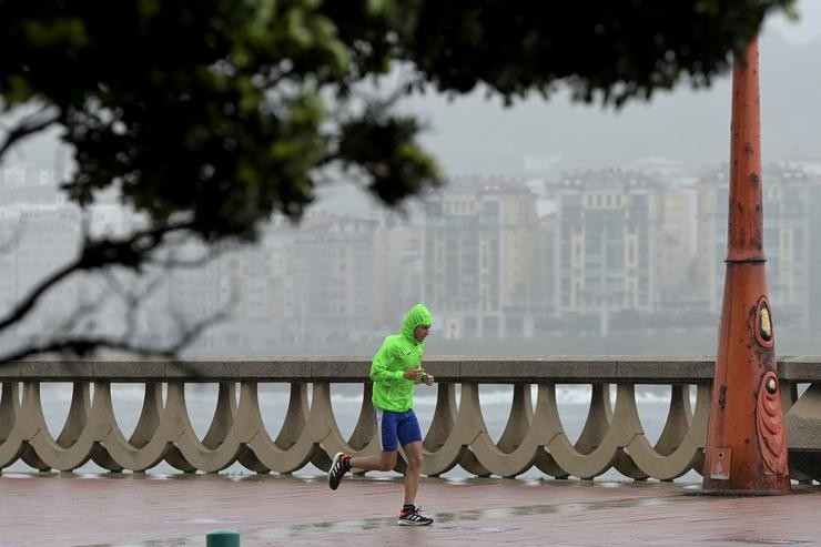 Un home, con chuvasqueiro, corre polo Paseo Marítimo da Coruña, a 19 de xuño de 2022 / M. Dylan