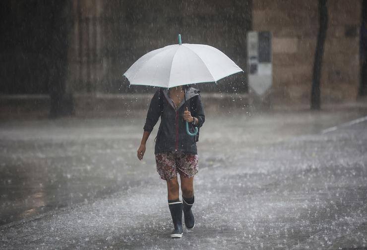 Unha persoa camiña cun paraugas baixo a choiva 