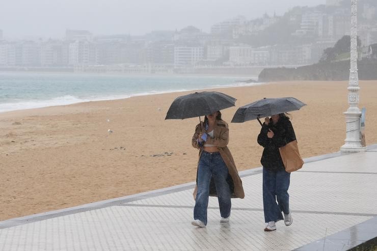 Dúas mulleres camiñan con paraugas na praia de Ondarreta, a 14 de outubro de 2023, en San Sebastián, Guipúzcoa, País Vasco (España).. Unanue - Europa Press 