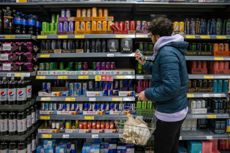 Mozo comprando bebidas enerxéticas nun supermercado 
