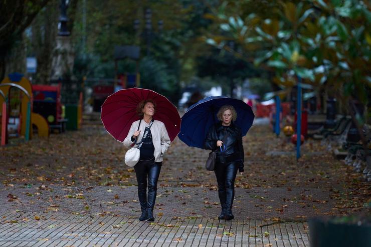 Varias persoas cóbrense da choiva e o vento con paraugas, a 20 de outubro de 2023 