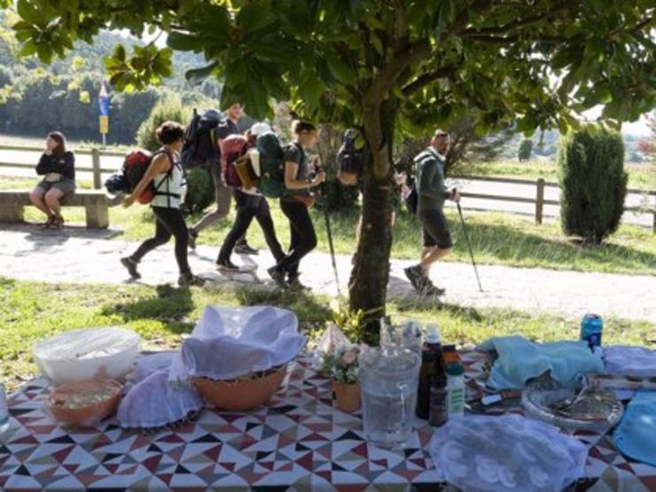 Peregrinos pasando xunto a unha mesa de picnic 