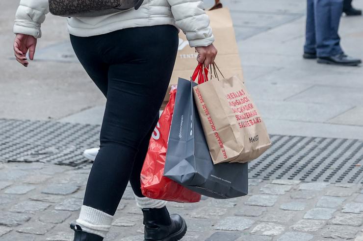 Unha persoa camiña con varias bolsas de compras  das rebaixas 