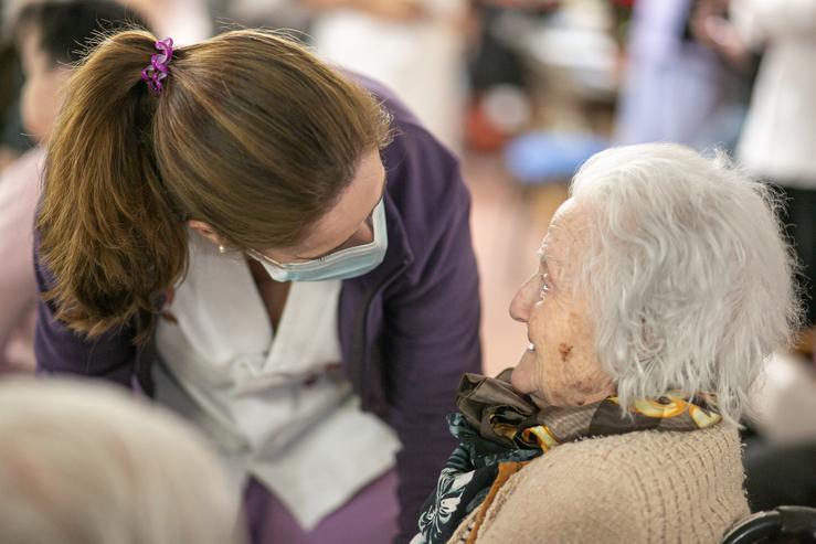 Persoa anciá pensionista sendo atendida por unha coidadora nunha residencia 