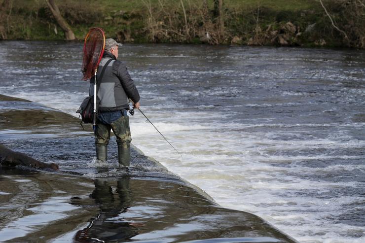 Un pescador, lanza a cana no río, durante o primeiro día de tempada de pesca fluvial 