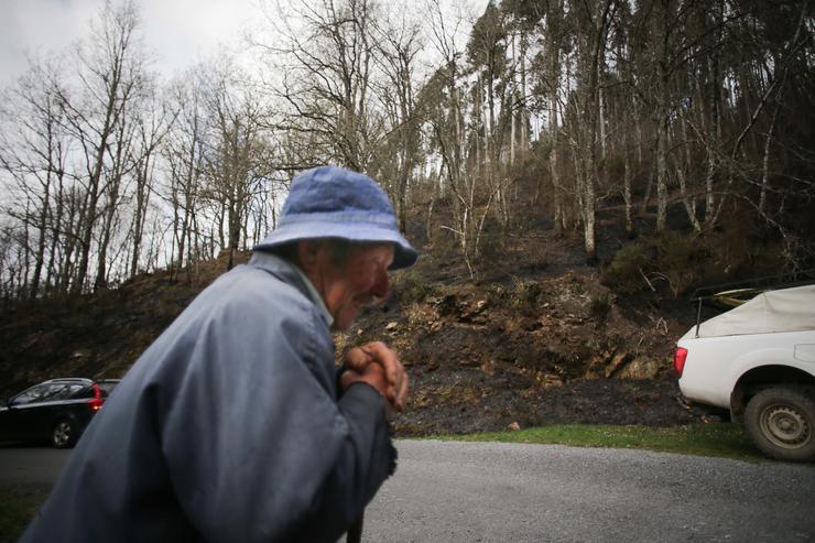 Un home camiña xunto ao monte queimado por un incendio forestal en Baleira / Europa Press