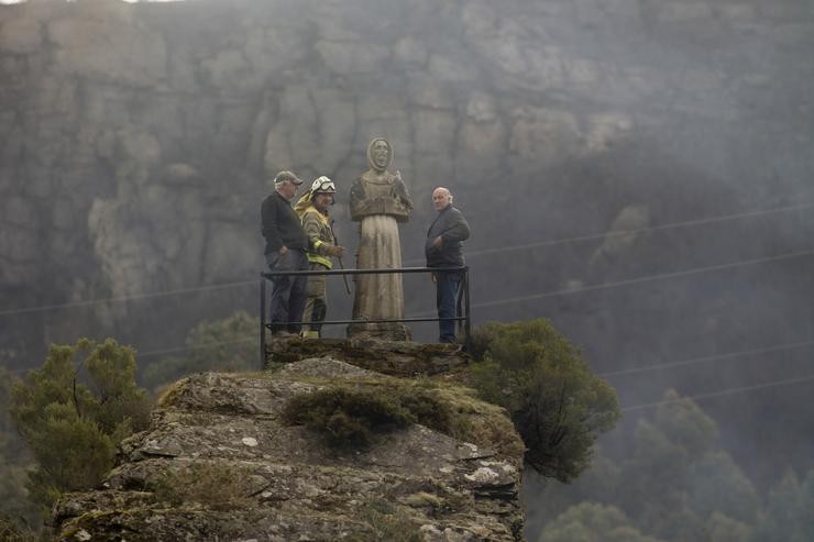 Dous homes e un garda forestal observan o monte queimado por un incendio forestal en Baleira 