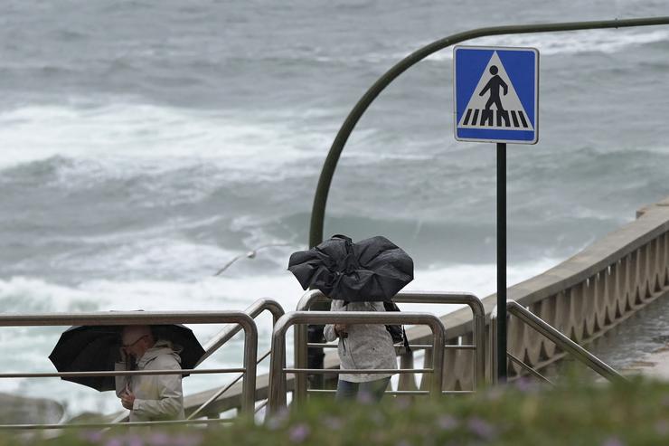 Dúas persoas con paraugas camiñan polo Paseo Marítimo da Coruña / Europa Press
