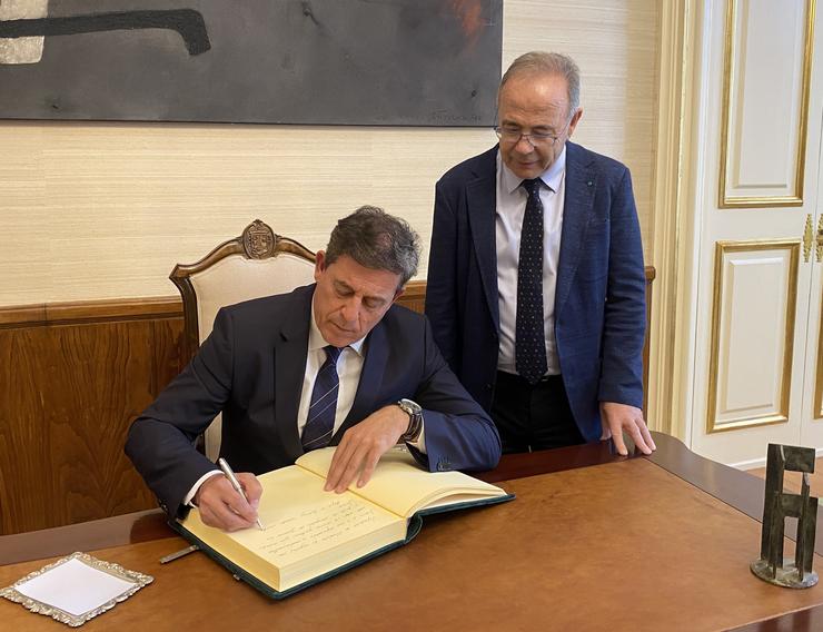 O delegado do Goberno en Galicia, José Ramón Gómez Besteiro, firma no libro oficial do Concello de Santiago acompañado polo alcalde, Xosé Sánchez Bugallo. DELEGACIÓN DO GOBERNO / Europa Press