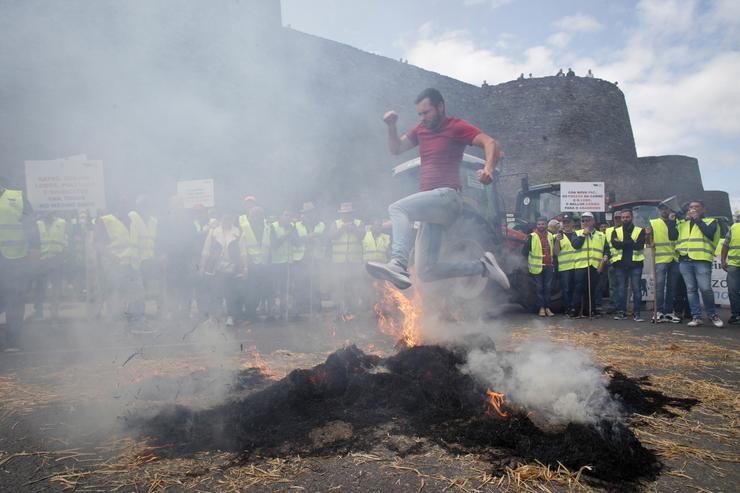 Un gandeiro salta unha fogueira de palla durante unha manifestación na Muralla de Lugo que colapsou cunha tractorada o centro de Lugo /  Europa Press / Europa Press