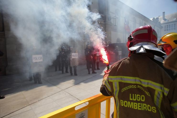 Un bombeiro de consorcios provinciais suxeita unha bengala de fume de cor durante unha protesta ante a sede da Xunta, a 23 de maio de 2023, en Lugo, Galicia (España). Os bombeiros de consorcios provinciais maniféstanse en Lugo en defensa de melloras. Carlos Castro - Europa Press / Europa Press