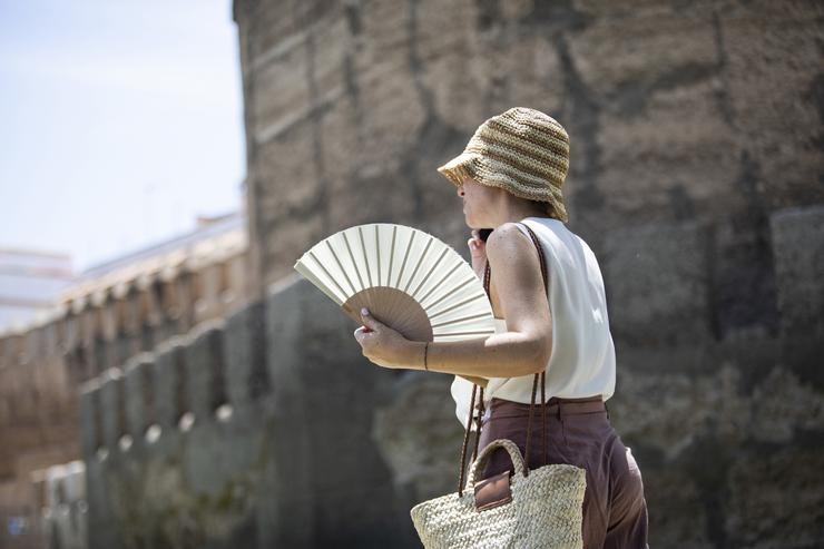 Unha muller protéxese do sol con chapeu e abanico 