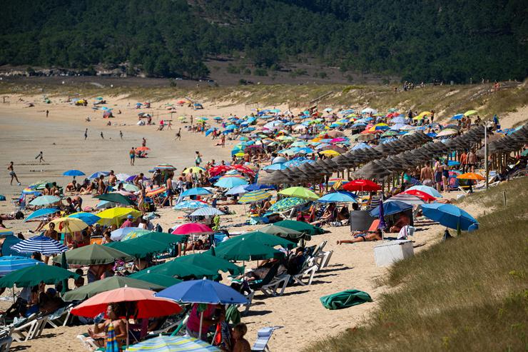 Varias persoas refúxianse do sol baixo antucas.. Elena Fernández - Europa Press 