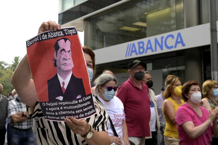 Unha persoa sostén unha pancarta durante a manifestación contra o peche de oficinas da entidade Abanca ante a sede de Abanca na Coruña, a 2 de setembro de 2021, na Coruña / M. Dylan - Arquivo