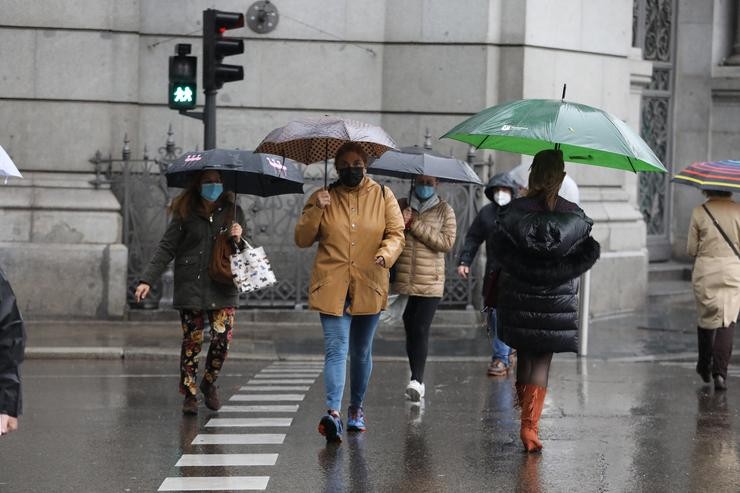 Transeúntes camiñan polo centro da capital protexéndose da choiva con paraugas 