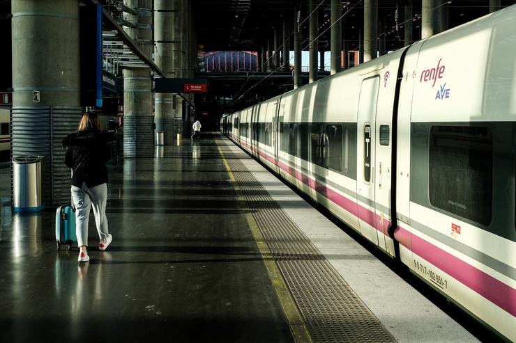 Unha muller camiña pola plataforma xunto a un tren de AVE de Renfe estacionado nas vías da Estación de Atocha. JESÚS HELLÍN 