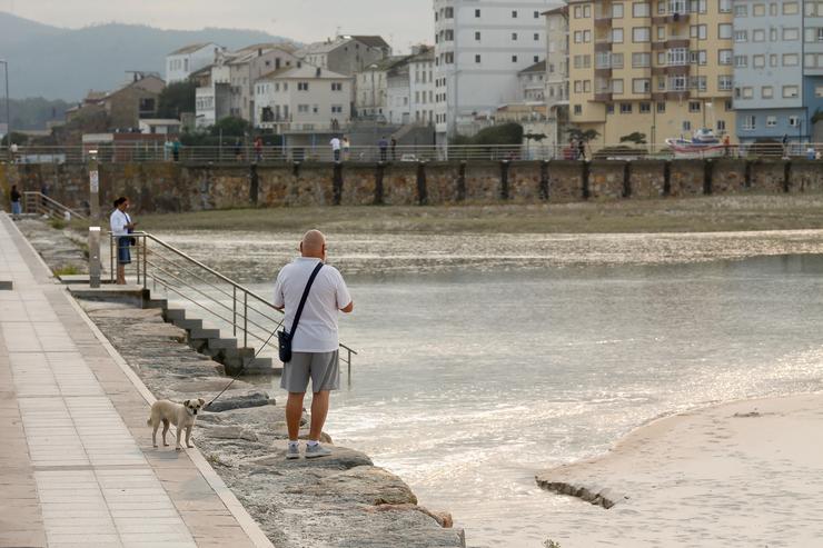 Arquivo - Varias persoas pasean durante a pleamar no espigón de Foz, xunto á praia da Rapadoira 