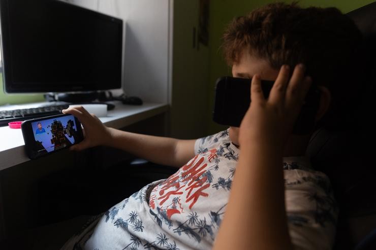 Un neno usa o teléfono móbil e unha tablet. Eduardo Parra, Arquivo 