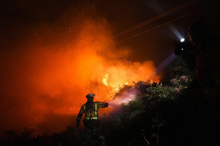 Un bombeiro trata de extinguir o lume 