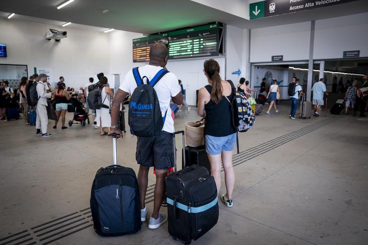 Varias persoas esperan con maletas e observan os carteis de saídas, na estación de Chamartín Clara Campoamor 