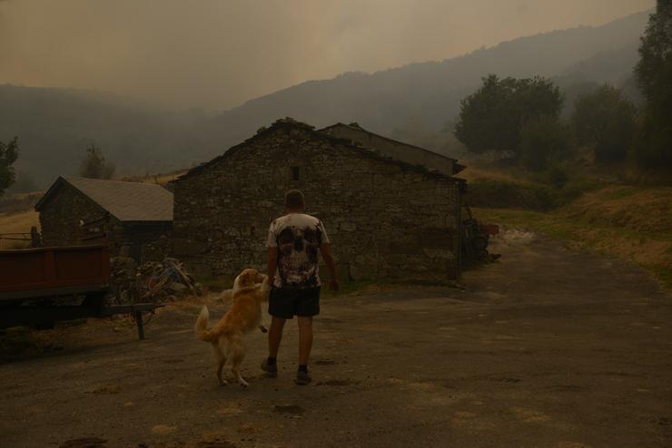 Unha persoa co seu can observa o incendio en Requeixo, a 11 de agosto de 2025, en Chandrexa de Queixa, Ourense, Galicia (España).. Rosa Veiga - Europa Press