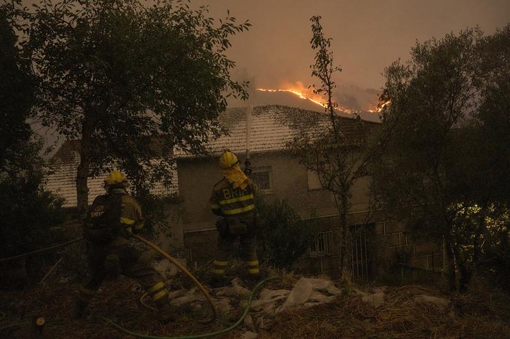 Varios bombeiros forestais tratan de extinguir un lume 