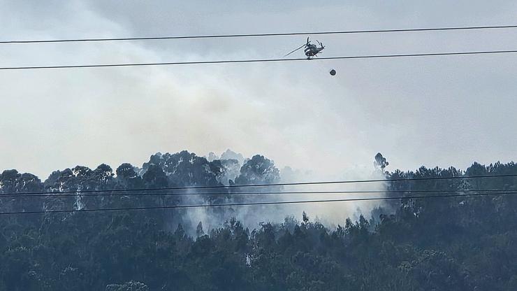 Helicóptero facendo a solta de auga enriba do lume no lugar do Santiaguiño do Monte, en Padrón 