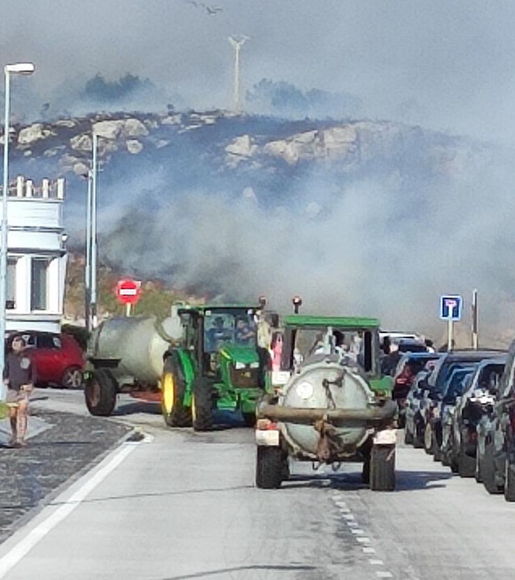 Tractores cargando auga no porto de Corme para axudar nas tarefas de extinción do lume que ameaza vivendas en Ponteceso 