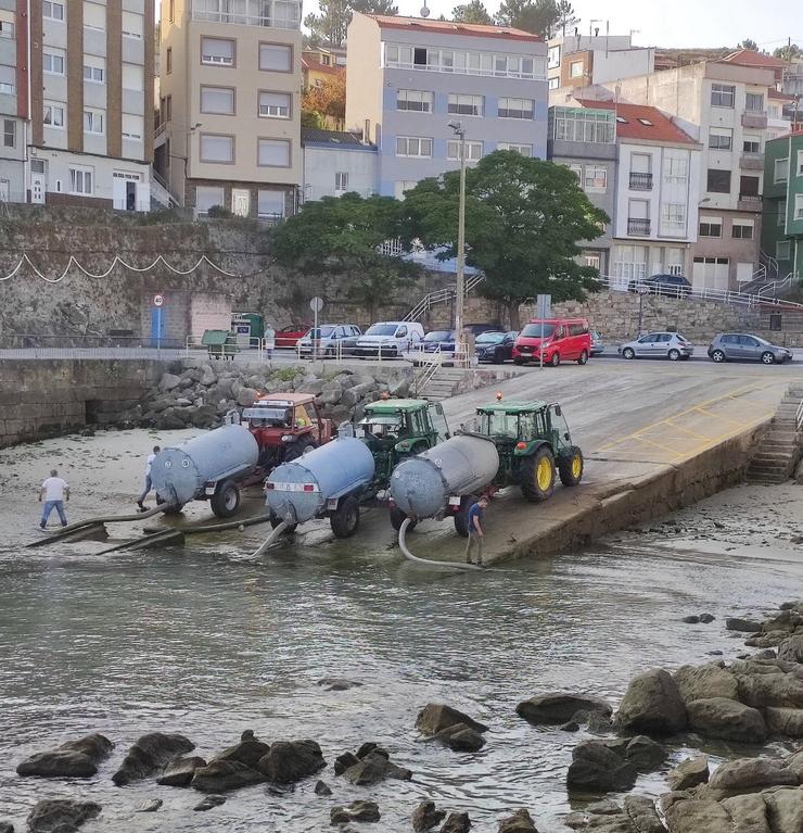 Tractores cargando auga no porto de Corme para axudar nas tarefas de extinción do lume que ameaza vivendas en Ponteceso 