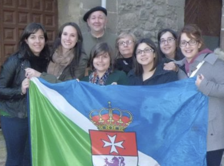 O grupo de alumnas da Universiade de Vigo que estudia a Fala , o galego de Extremadura, sostendo a bandeira de San Martiño de Trebello acompañadas polo profesor Xosé Henrique Costas