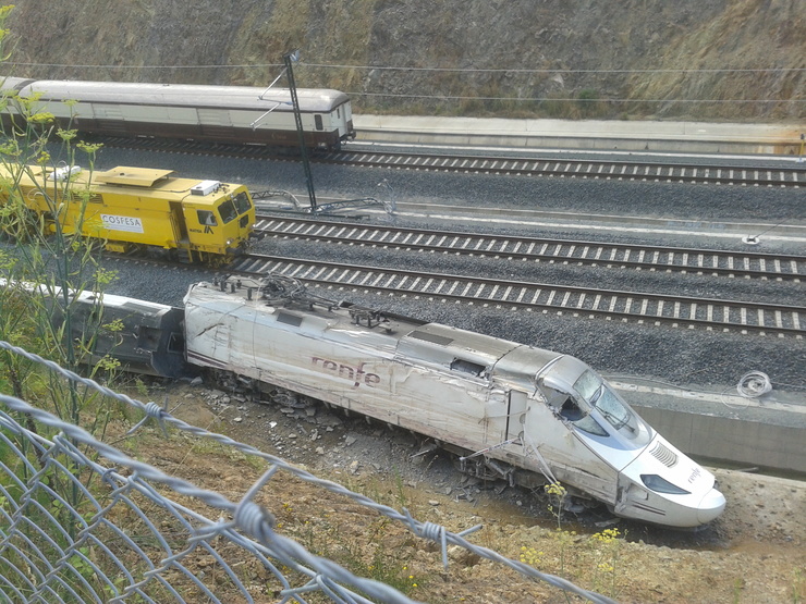 Un tren FEVE pasa xunto a máquina do Alvia sinistrado.