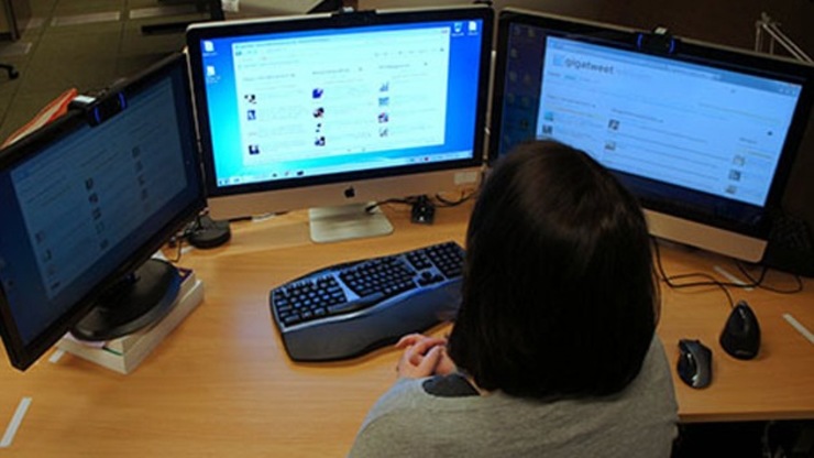 Unha muller traballa diante de varias pantallas de ordenador.