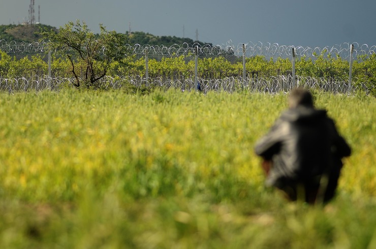 Un home observa o aramado que arrodea o campo de refuxiados de Idomeni 