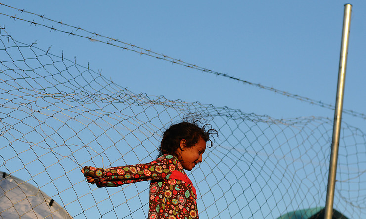 O sorriso desta nena refuxiada en Idomeni desafía a tristura do muro de arame que a priva dunha vida segura en Europa / Miguel Núñez.