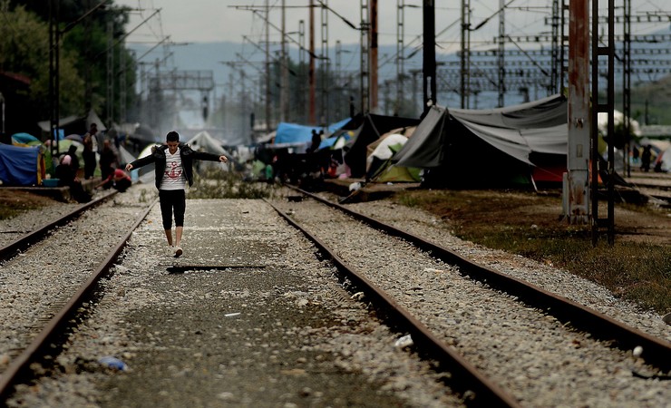 Un mozo camiña polo medio das vías ferroviarias, no campamento de refuxiados improvisado na estación de Idomeni 