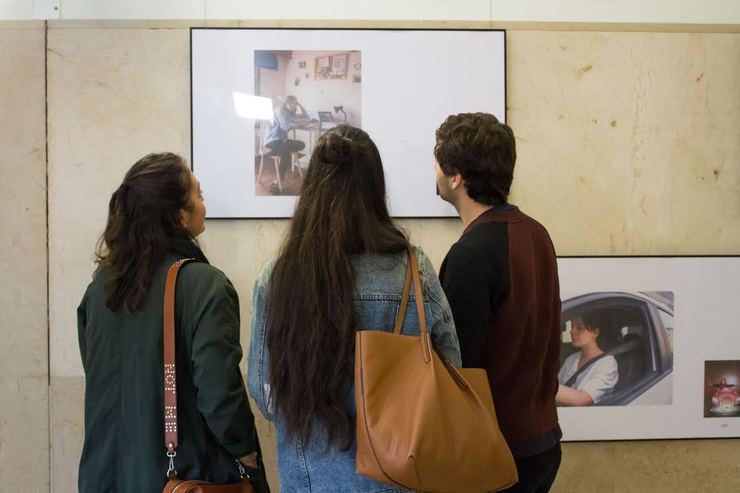 Un grupo de mozos observa fotografías da exposición "Orixes" dos estudantes da Facultade de Ciencias da Comunicación